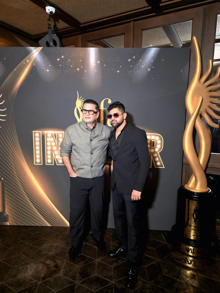 Two guests standing beside an IIFA Insiders backdrop and trophy display